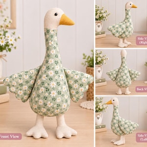 Pode incluir: Um ganso de pelúcia com corpo de tecido verde claro com estampa de margaridas brancas, cabeça cor de creme e bico amarelo mostarda. O ganso tem asas estendidas, pescoço longo e pés palmados, mostrado de frente, de lado e de costas.