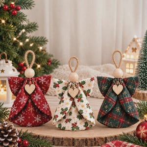 Op de afbeelding: Drie stoffen engelhangers met houten kraalhoofden en kleine houten hartjes. Eén is rood met witte sneeuwvlokken, één is crème met hulstblaadjes en bessen, en één is groen en rood geruit met gouden metallic draaddetails.