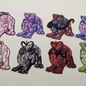 Puede incluir: Ocho pegatinas de colores en forma de cerebro con diferentes expresiones. Cada pegatina tiene un color y un diseño único, incluyendo rosa, morado, azul, gris, rojo, verde y negro.