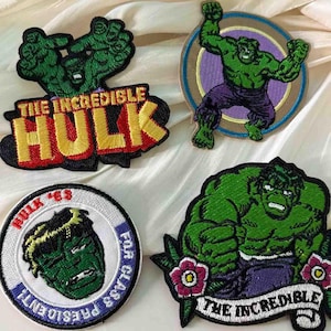 以下が含まれることがあります： ハルクの刺繍パッチ4枚。1枚には赤と黄色の文字で「THE INCREDIBLE HULK」と書かれています。もう1枚は紫色のズボンをはいたハルクが円の中に描かれています。3枚目のパッチには「HULK '63」と書かれています。最後のパッチには「THE INCREDIBLE」と書かれています。