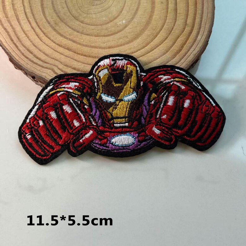 May include: Embroidered Iron Man patch showing the character's helmet and chest. The patch is red, gold, and purple, with black edging. The dimensions are 11.5 x 5.5 cm. The patch is designed to be ironed or sewn onto fabric.