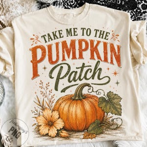 Könnte beinhalten: Ein cremefarbenes T-Shirt mit einem Grafikdruck, der den Text "TAKE ME TO THE PUMPKIN PATCH" in Dunkelgrün und verwaschenem Orange zeigt. Das Design umfasst einen großen orangefarbenen Kürbis, eine hellorange Blume und grüne Blätter.