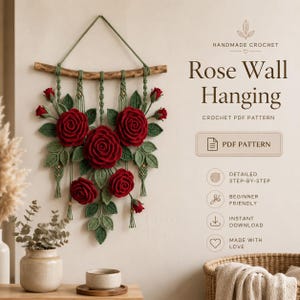 May include: A handmade crochet rose wall hanging featuring large red roses and green leaves. The wall decor is suspended from a wooden branch with macrame detailing. The text on the image reads "Rose Wall Hanging" and "Crochet PDF Pattern".