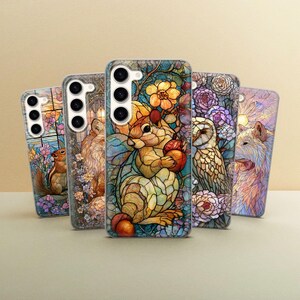 Può includere: Una collezione di cinque cover per smartphone con colorate illustrazioni in stile vetrata. I disegni raffigurano vari animali, tra cui uno scoiattolo, un gufo e un lupo, circondati da intricati motivi floreali e vivaci disegni di fogliame.