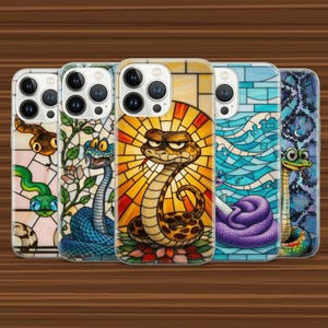 以下が含まれることがあります： ステンドグラス風のヘビのイラストが描かれた5つのスマートフォンケース。各ケースには、青、黄、オレンジ、紫などの鮮やかな色使いで、幾何学模様や花柄を背景にしたユニークなヘビのデザインが施されています。