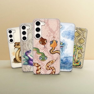 May include: Five rectangular smartphone cases arranged in a row, each featuring unique snake-themed illustrations. The designs include various cartoon snakes in different colours, patterns, and styles, set against backgrounds of solid colours or snake skin textures.