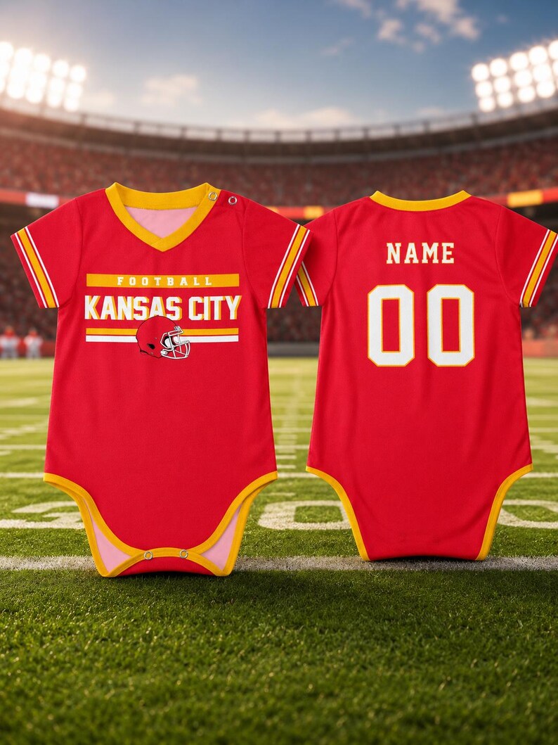May include: A red baby bodysuit with yellow trim, featuring the text "KANSAS CITY" and a football helmet graphic on the front. The back displays the word "NAME" above the number "00" in white with yellow outlines, mimicking a sports jersey style.