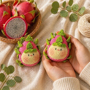 May include: Two crocheted dragon fruit plushies with smiling faces, held in hands. The plushies are pink, green, and yellow, resembling the fruit. A basket of fresh dragon fruit is in the background, with one cut open to show the white flesh and black seeds.