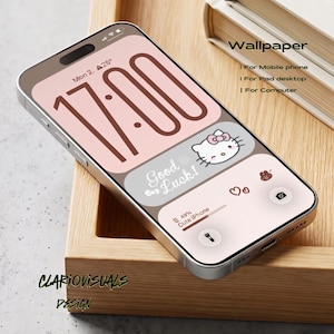 May include: A smartphone displaying a digital wallpaper with a soft pink and brown color palette. The screen shows the time 17:00, a Hello Kitty graphic with the text Good Luck, battery status, and icons for a camera and flashlight.