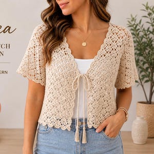 May include: A cream-colored, shell stitch cardigan with short sleeves and a tie closure. The crochet pattern is available in sizes XS-2XL. The image includes the text "Solea Shell Stitch Cardigan Crochet Pattern" and an "Instant Download" icon.