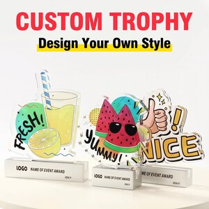 May include: Custom acrylic trophies with colorful fruit and drink designs. One trophy features a lemon and a glass of lemonade with a straw. Another has watermelon slices wearing sunglasses. The third trophy has a thumbs up and the word "NICE!"