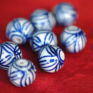 May include: A collection of blue and white ceramic beads with intricate patterns. The beads are round and have a glossy finish.