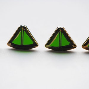 May include: Four gold-colored triangular buttons with green glass centers.