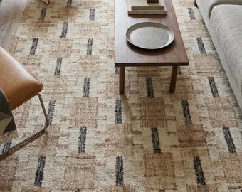 May include: A rectangular area rug featuring a woven pattern of cream, tan, and black blocks. The design consists of alternating light and dark rectangular shapes arranged in a grid-like formation, creating a textured surface across the floor.