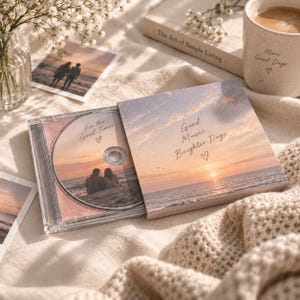 May include: A clear plastic CD case containing a disc with a sunset beach scene and the text 'For the Good Times'. The cover features a matching sunset landscape with the text 'Good Music Brighter Days' and a small heart symbol printed on it.