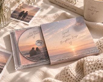 Op de afbeelding: Een doorzichtig plastic cd-doosje met een schijfje waarop een strandscène bij zonsondergang en de tekst 'For the Good Times' staat. De hoes toont een bijpassend zonsonderganglandschap met de tekst 'Good Music Brighter Days' en een klein hartje.