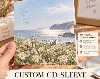 Op de afbeelding: Een vierkante papieren cd-hoes met een landschapsfoto van een veld met witte madeliefjes die uitkijken over een glinsterende blauwe oceaan. De tekst "a playlist for brighter days" staat linksboven gedrukt. Rechts is een duimuitsparing zichtbaar.