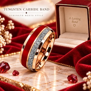 May include: A tungsten carbide band featuring a polished gold-tone finish, a central red inlay, and a textured silver-tone glitter stripe. The ring is displayed near a red velvet box with the text A Lasting Bond and a heart symbol printed inside.