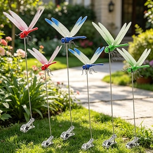 Puede incluir: Una colección de estacas de jardín con forma de libélula de colores. Cada estaca presenta una libélula de metal con alas translúcidas en rojo, azul y verde. Las libélulas están unidas a finas varillas metálicas con clips.