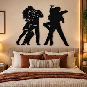 Op de afbeelding: Een zwart metalen wanddecoratie met twee verschillende silhouetten van dansende paren. De linkerfiguur toont een paar in een nauwe omhelzing, terwijl de rechterfiguur een paar in een dynamische danshouding op een beige muur weergeeft.