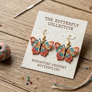 Può includere: Orecchini a farfalla all'uncinetto con ganci color oro, presentati su una scheda con il testo "THE BUTTERFLY COLLECTIVE" e "MINIATURE CROCHET BUTTERFLIES". Sono presenti anche un gomitolo di lana, un uncinetto e delle perline.