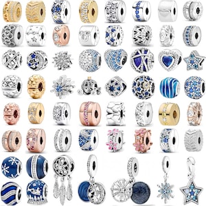 May include: A collection of silver and gold-toned charm beads with various designs. Some beads feature clear and blue crystals, stars, flowers, and other decorative elements. The charms are designed to be added to a bracelet or necklace.