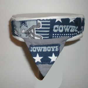 May include: A white and blue fabric headband with a football helmet, stars, and the word "COWBOYS" printed on it. The headband has a grey fabric flap with the word "COWBOYS" printed on it.