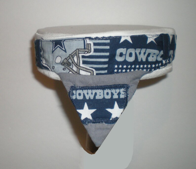 May include: A white and blue fabric headband with a football helmet, stars, and the word "COWBOYS" printed on it. The headband has a grey fabric flap with the word "COWBOYS" printed on it.
