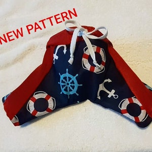 May include: A blue and red fabric dog bandana with a nautical theme. The bandana features anchors, life preservers, and steering wheels. The text "NEW PATTERN" is visible in the top left corner of the image.