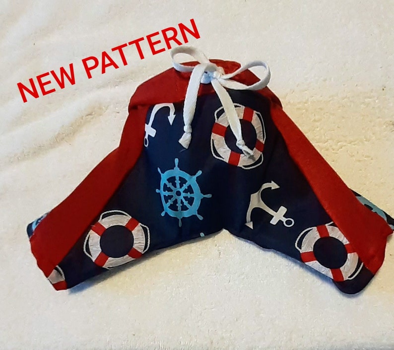 May include: A blue and red fabric dog bandana with a nautical theme. The bandana features anchors, life preservers, and steering wheels. The text "NEW PATTERN" is visible in the top left corner of the image.
