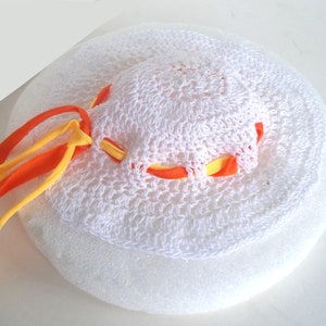 May include: White crocheted sun hat with orange and yellow ribbon trim.
