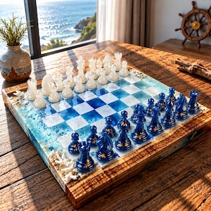 Könnte beinhalten: Ein quadratisches Schachspiel mit einem Brett aus blau-weißer Harzoberfläche im Ozean-Design, eingerahmt von Naturholz. Das Set enthält Schachfiguren aus weißem und dunkelblauem Harz, wobei die blauen Figuren mit kleinen goldenen Blumen verziert sind.