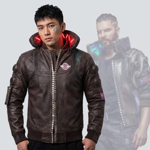 May include: Brown leather jacket with a studded zipper, a hood with red lighting, and a patch on the chest. The jacket has a bomber-style design with ribbed cuffs and a waistband. The jacket is worn by a person with futuristic cybernetic enhancements.