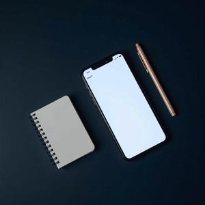May include: A smartphone with a blank white screen, a spiral-bound notebook, and a rose gold pen are arranged on a dark blue surface. The phone displays the word "Charts" at the top. The notebook is light gray.