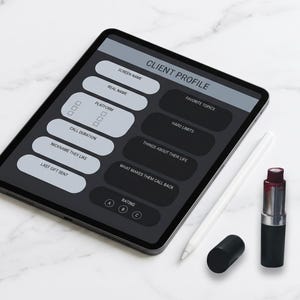May include: A digital tablet displaying a "Client Profile" form with fields for screen name, real name, and other details. A white stylus and a tube of lipstick are next to the tablet. The background is a white marble surface.