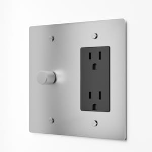 May include: A square brushed silver wall plate featuring a circular knurled dimmer knob on the left and a vertical black dual electrical outlet on the right. The metal plate is secured to the wall with four small flathead screws at the corners.