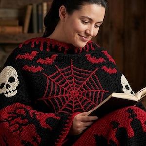 May include: A black and red crocheted Halloween-themed shawl featuring a spiderweb, bats, and skull designs. The shawl is wrapped around a person reading a book. The color scheme is black and red.