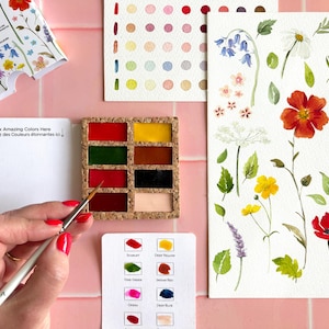 May include: A watercolor set featuring a cork palette with eight paint pans, a mixing card with the text Mix Amazing Colors Here, a color swatch card, and a floral illustration sheet. A paintbrush is held over the red paint pan.