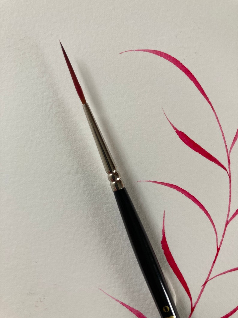 May include: A close-up of a black and silver paintbrush with a red watercolor wash in the background.