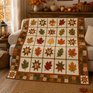 May include: A rectangular quilt featuring a grid of squares with various autumn leaf patterns and star motifs in shades of orange, red, yellow, and green. The quilt has a cream-colored background and a decorative border made of small patchwork squares.