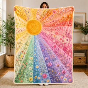 Könnte beinhalten: Eine rechteckige Wohndecke mit einem leuchtenden Sonnenstrahlen-Design und einem großen gelben Kreis in der Mitte. Die Decke zeigt ein regenbogenfarbenes Spektrum, wobei jeder strahlenförmige Abschnitt mit verschiedenen Blumenmustern verziert ist.