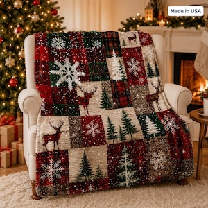 Può includere: Una coperta in peluche con un design patchwork di quadrati a quadri rossi e verdi, fiocchi di neve bianchi, alberi sempreverdi e sagome di cervi. La coperta ha una consistenza morbida e mostra il testo Made in USA nell'angolo superiore.