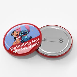 K&ouml;nnte beinhalten: Ein runder Ansteckbutton mit einem blauen Alien-Charakter und einem M&auml;dchen mit einer rosa Blume im Haar vor einem blauen Hintergrund mit gelben Sternen. Der Text "Definitely Not My 1st Visit!" steht in Wei&szlig; auf einem roten Banner.