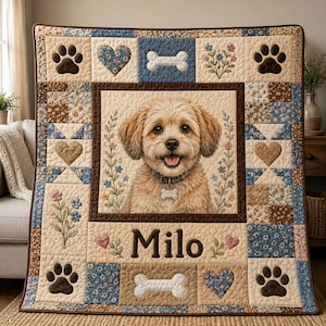 May include: A quilted throw blanket featuring a central portrait of a light brown dog wearing a collar with a tag. The quilt is decorated with paw prints, hearts, bones, and floral patterns in blue and tan, with the name Milo printed below.