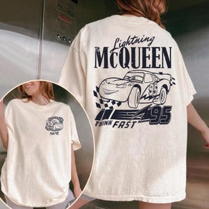 Pu&ograve; includere: T-shirt color crema con grafica di Saetta McQueen dal film Cars. Il retro mostra "Lightning McQueen" sopra un'illustrazione di auto, il numero "95" e "Think Fast". Il davanti presenta una grafica di auto pi&ugrave; piccola con la parola "NAME".