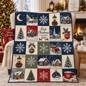 Könnte beinhalten: Eine gesteppte Wohndecke mit einem Gitter aus weihnachtlichen Quadraten, darunter verschneite Häuser, Tannenbäume, Schneeflocken, Laternen, Christbaumkugeln, ein Schlitten und eine Tasse. Das mittlere Quadrat zeigt den Text First Christmas in Our Home 2026.