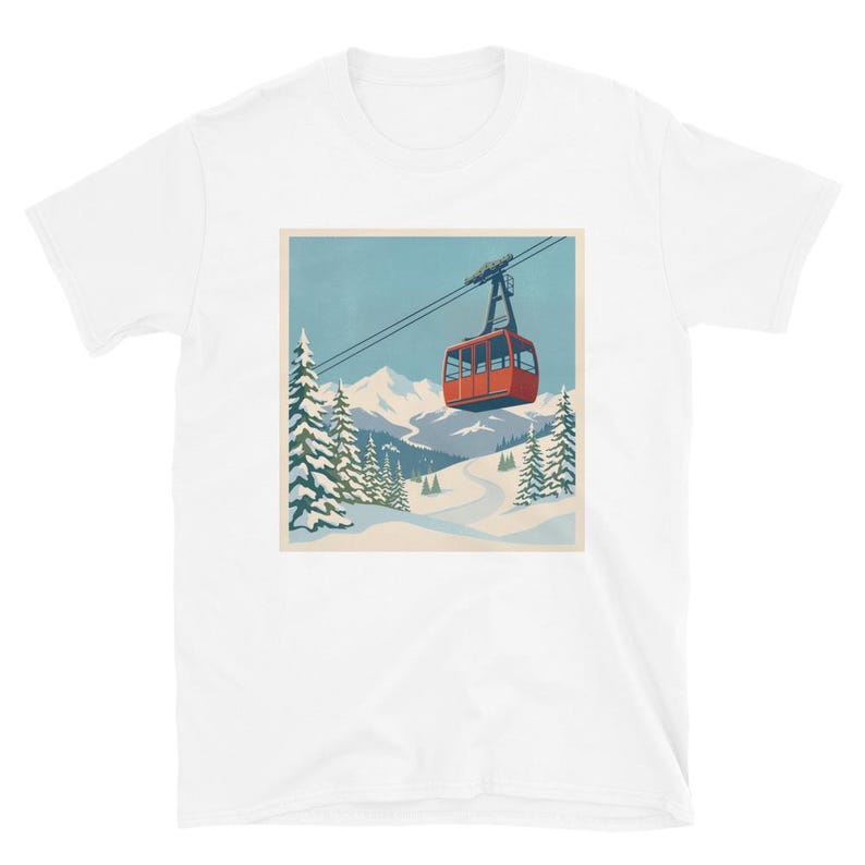 Puede incluir: Camiseta blanca con una ilustraci&oacute;n de estilo retro de un telef&eacute;rico rojo ascendiendo una monta&ntilde;a nevada. El dise&ntilde;o incluye pinos, una pista de esqu&iacute; sinuosa y un cielo azul, evocando un tema de deportes de invierno.