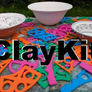 May include: Three ceramic bowls, two with intricate black line patterns and one plain white, surrounded by a collection of colourful plastic geometric stencils and tools. The word ClayKit is prominently displayed in large black letters across the centre.