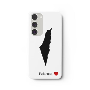 Peut inclure: Coque de téléphone blanche avec une silhouette noire de la Palestine. Le mot "Palestine" est imprimé en noir, avec un symbole de cœur rouge. La coque de téléphone possède un appareil photo à trois objectifs.