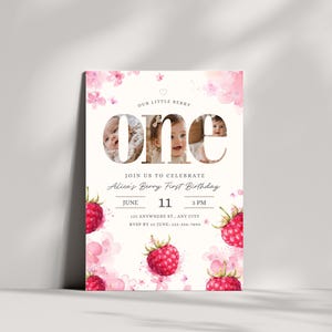 Puede incluir: Una invitación de cumpleaños con un fondo claro, con la palabra "ONE" con fotos de bebé en su interior. La invitación incluye el texto "Our Little Berry" y "Alice's Berry First Birthday". Las frambuesas y los motivos florales rosas de acuarela decoran el diseño.